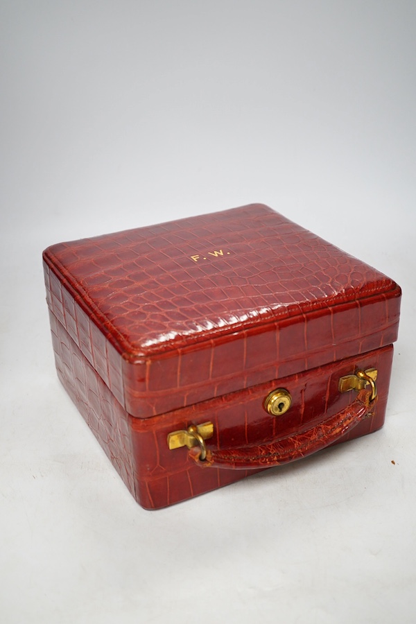 An early 20th century crocodile skin vanity case with glass jars, 21.5cm wide. Condition - fair, no key